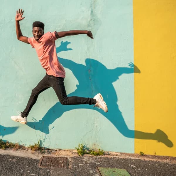 A man leaping energetically in front of a painted wall