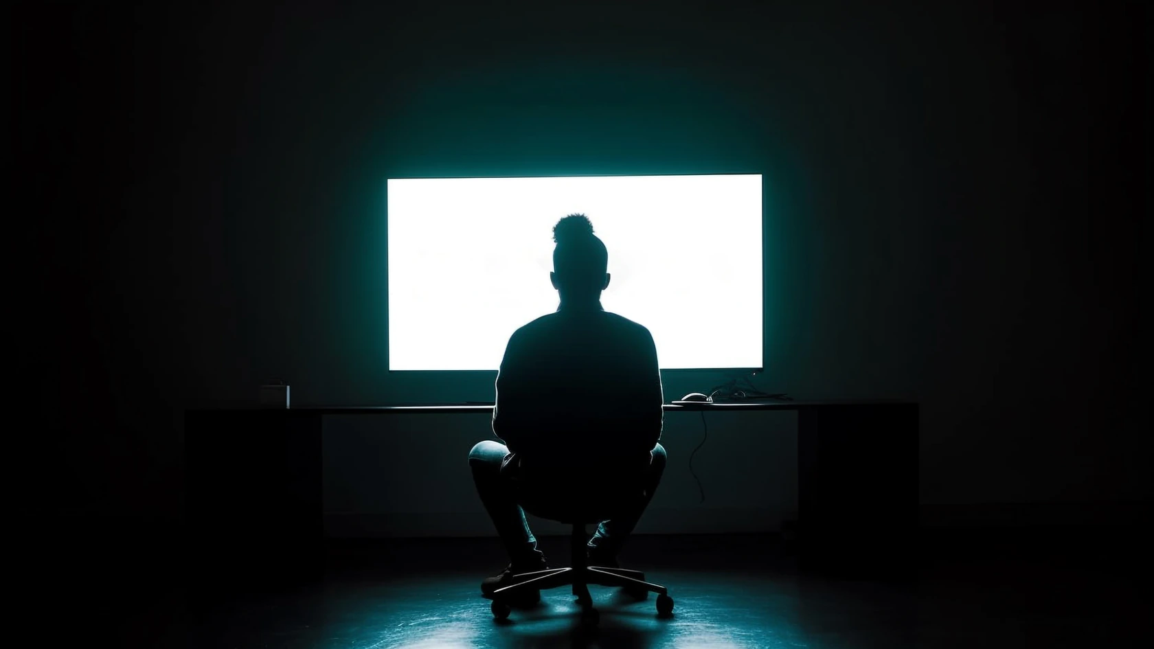 Silhouette of a person at a glowing computer in a dark office, representing informal shadow AI use at work