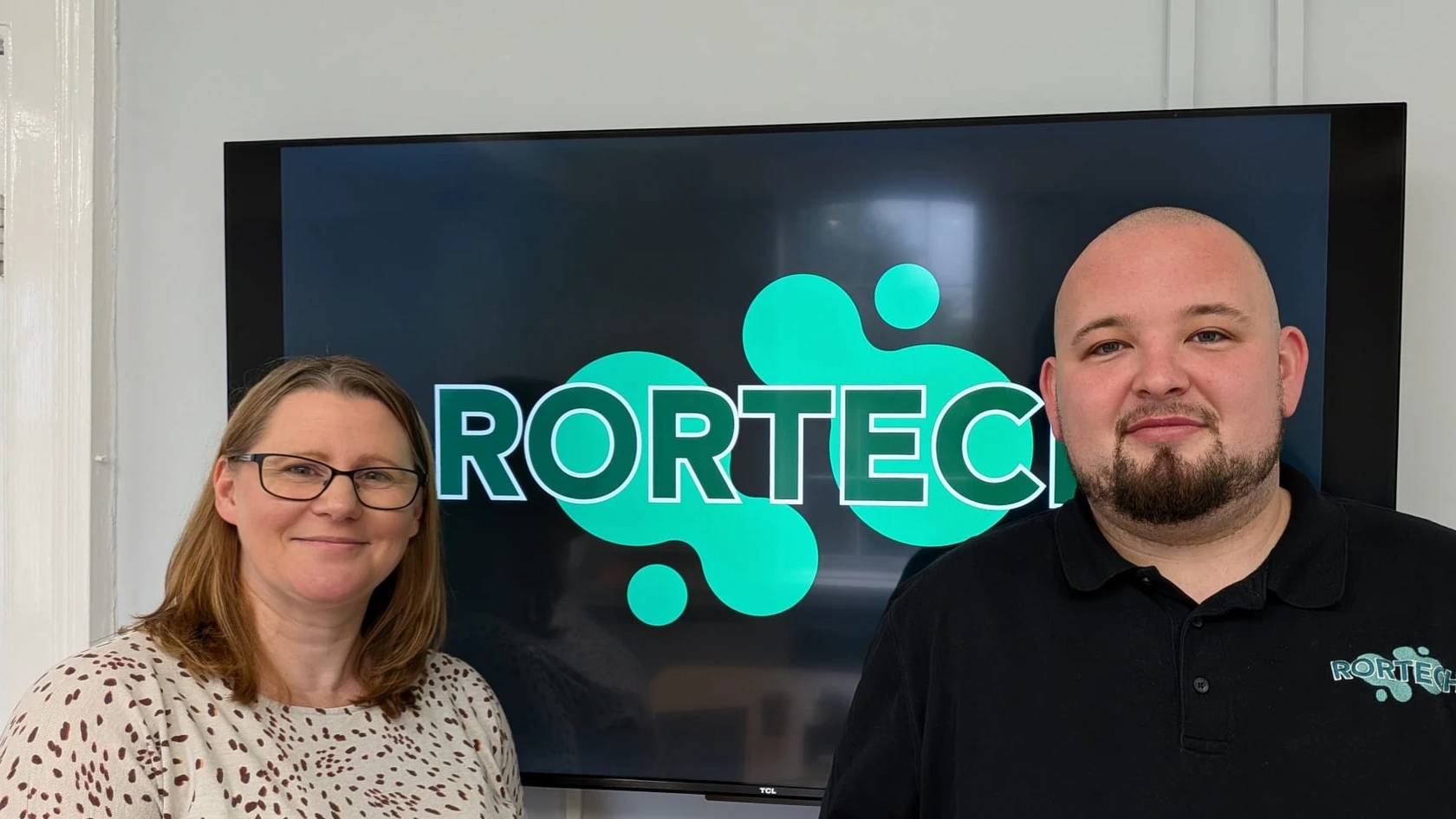 Shona Farmer and Adam Blackwell standing in front of a screen showing the RorTech logo